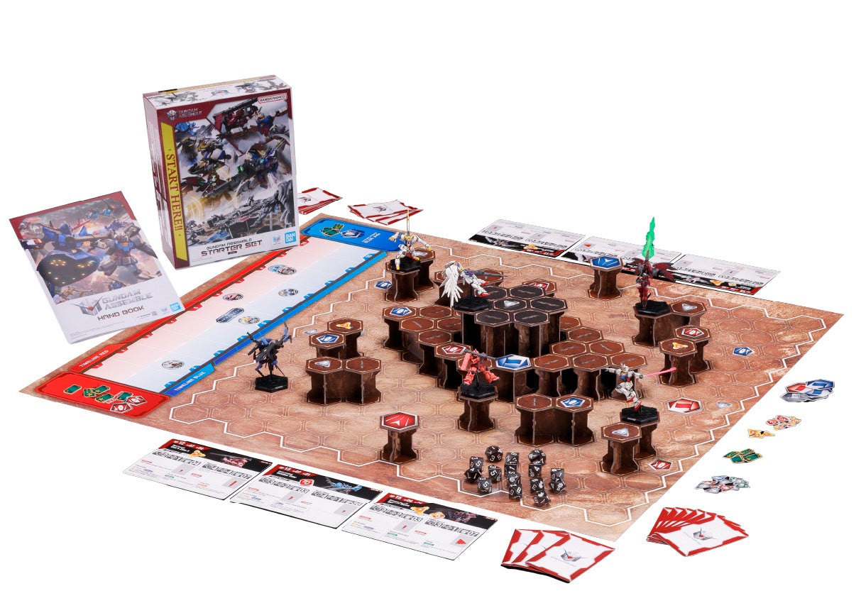 The Gundam Assemble Starter Set 01 box beside a laid-out game: a hex map with stacked brown terrain pillars, six small mobile suit miniatures, dice, tokens, unit cards and a handbook, on a white background.